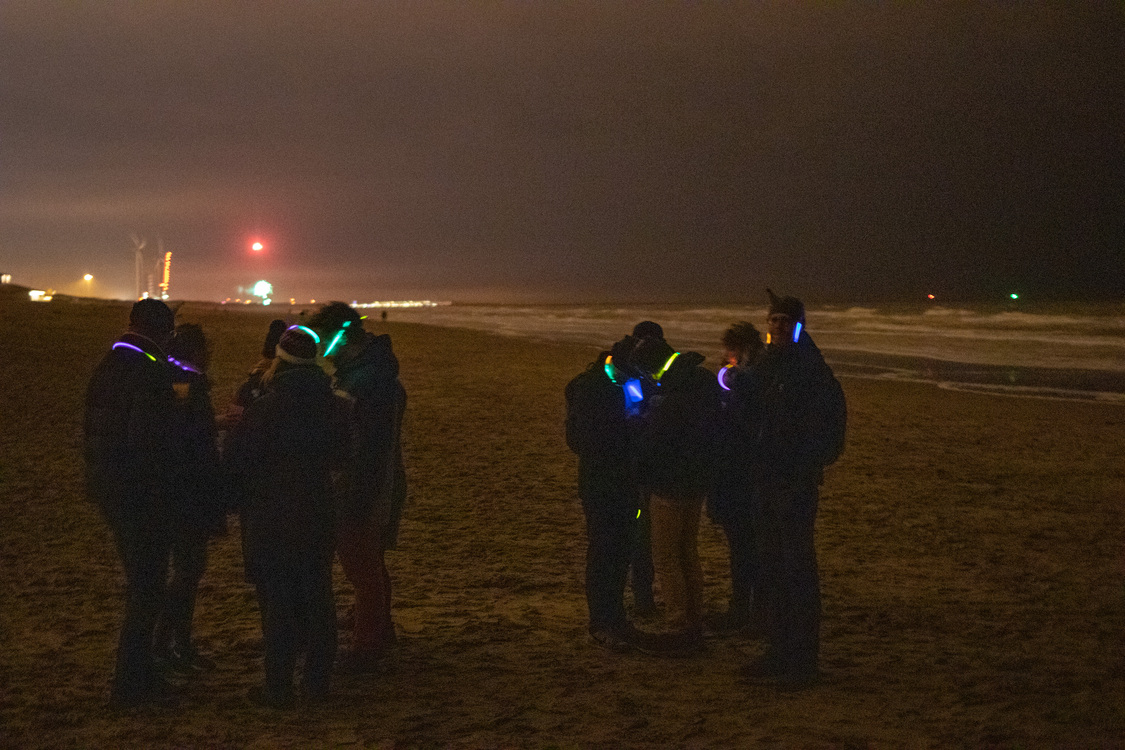 mensen met lichtjes op het strand, vuurwerk